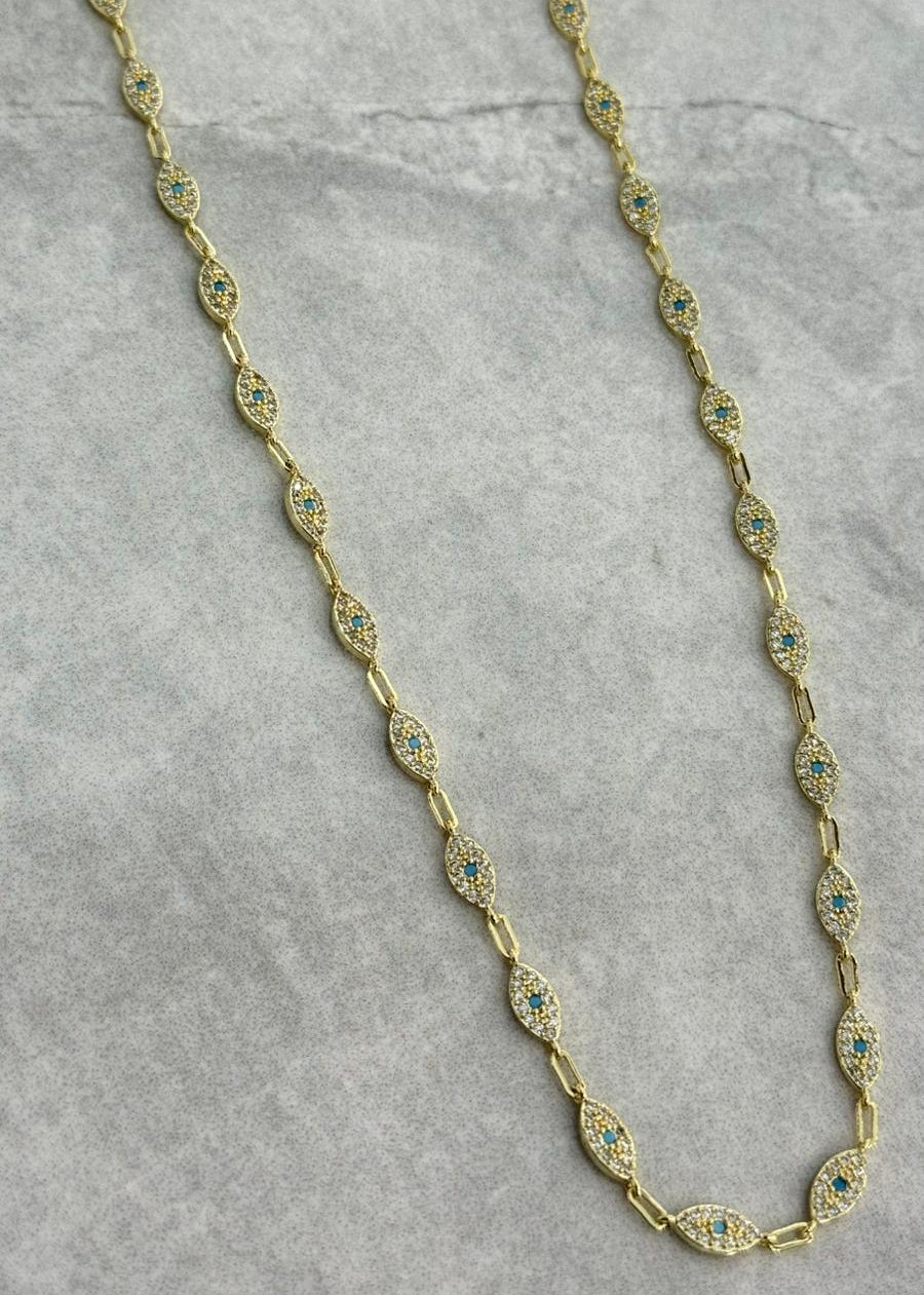 Gold necklace with green gemstones on a gray surface