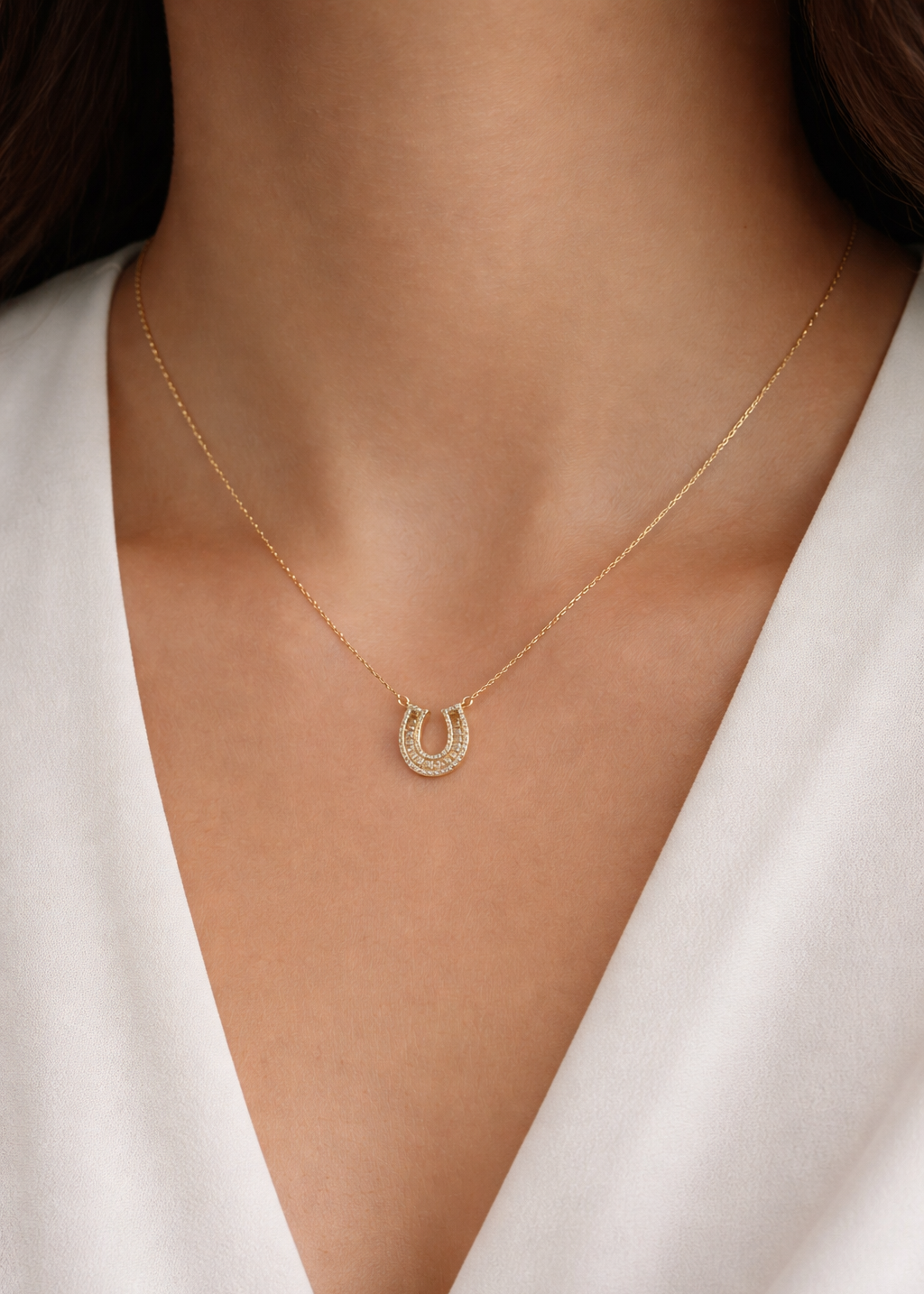 gold horseshoe crystal necklace on delicate chain worn on neckline