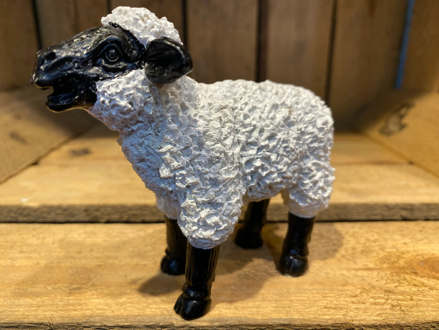 Miniature black and white sheep resin figurine standing with head raised in natural pose