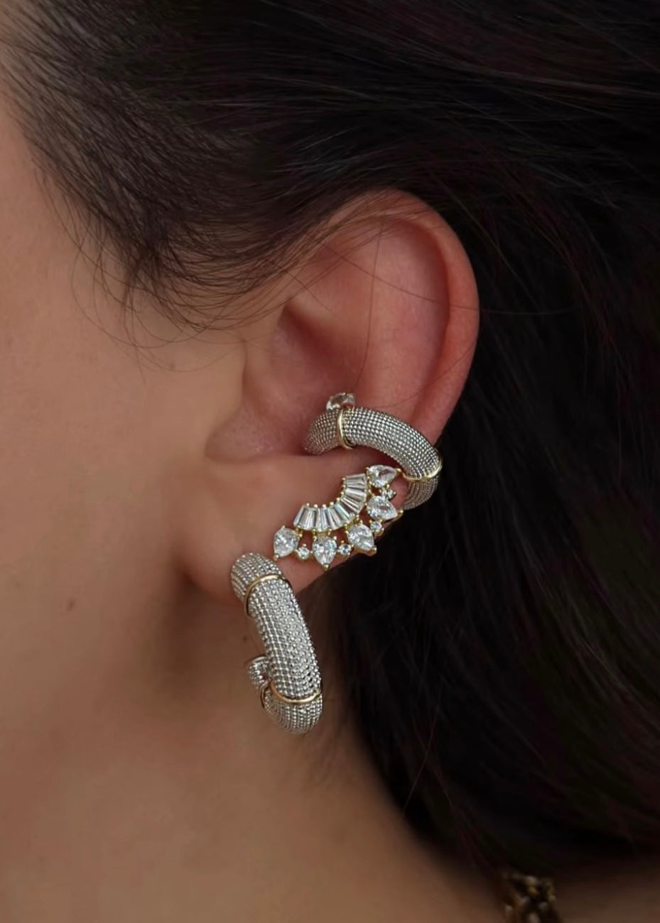 Close-up of an ear wearing a decorative earring with a dark background