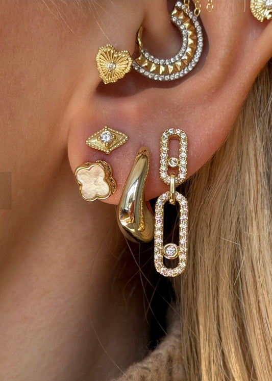 Close-up of an ear with multiple gold earrings.