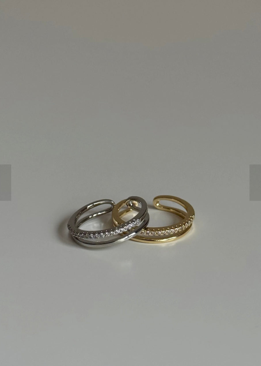 Two rings, one silver and one gold, on a light gray background