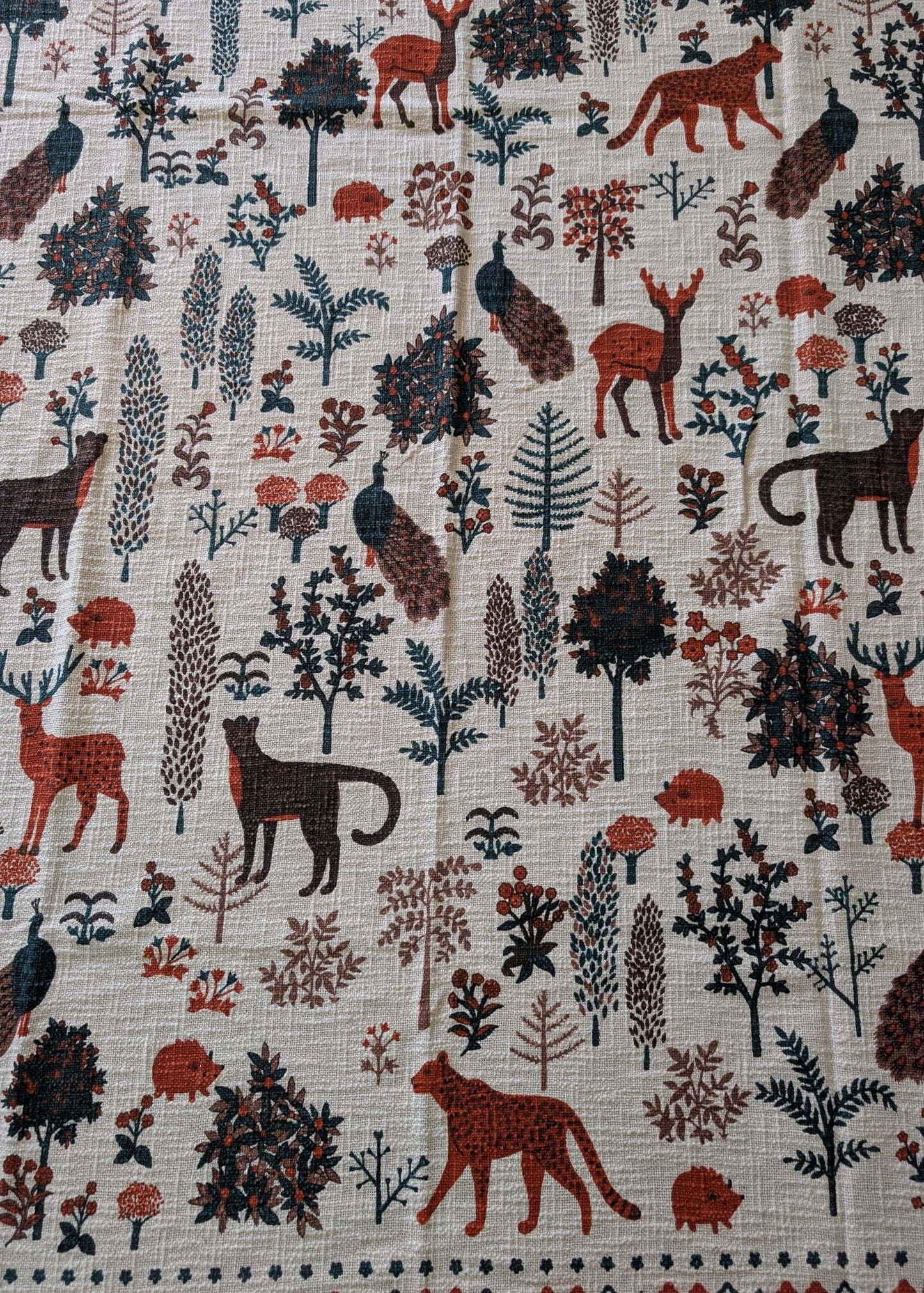 Fabric with a nature-themed pattern featuring animals and plants on a beige background