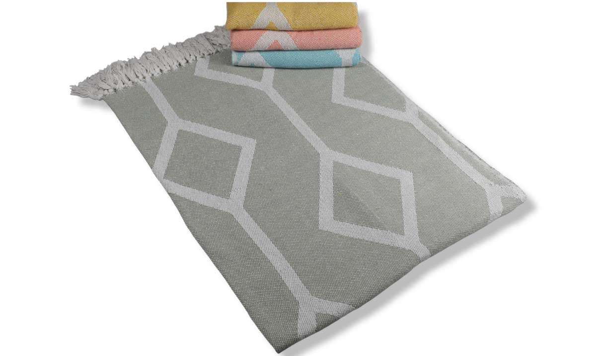 Gray geometric patterned rug with colorful folded towels on a white background