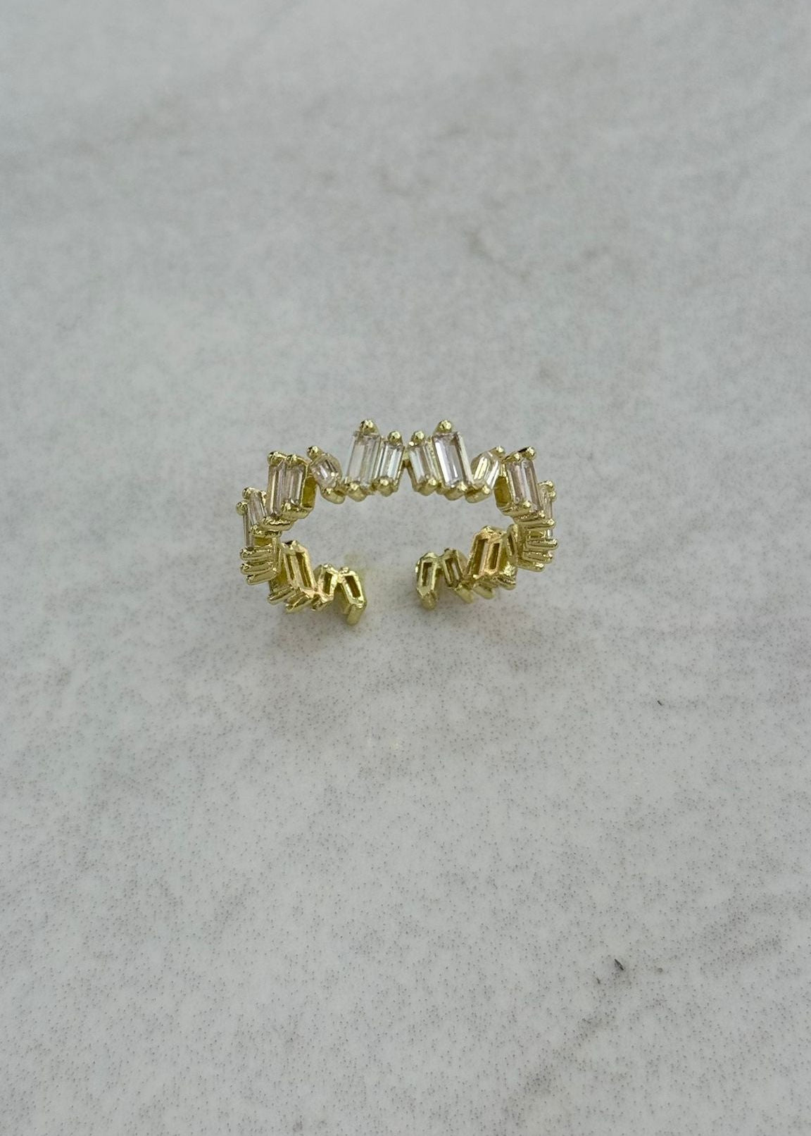 Gold open ring with baguette-cut zirconia stones on a minimal band