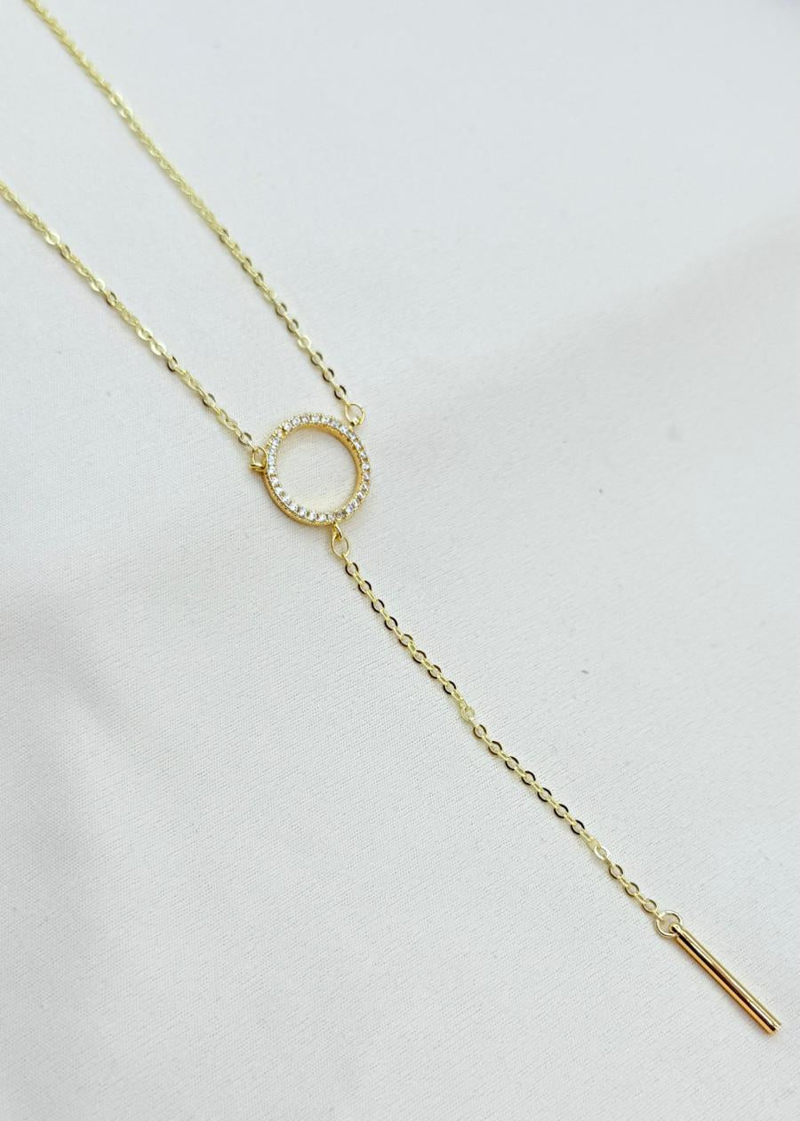 Gold necklace with a delicate chain and small pendant on a light background