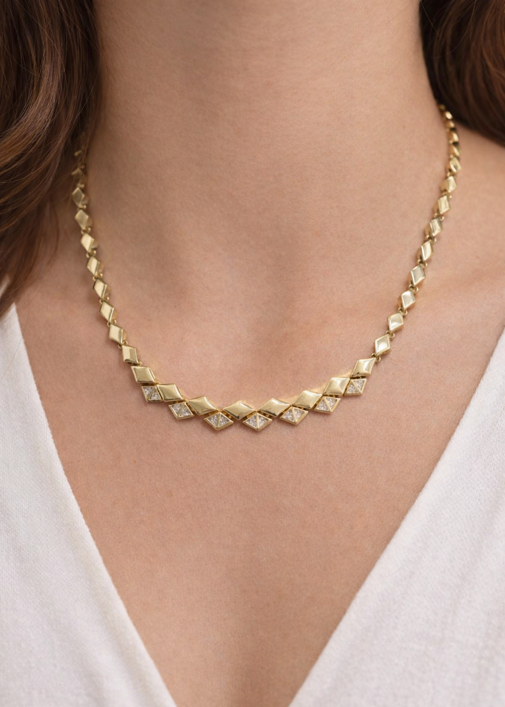 Gold geometric link necklace with diamond-shaped crystal accents worn on neck