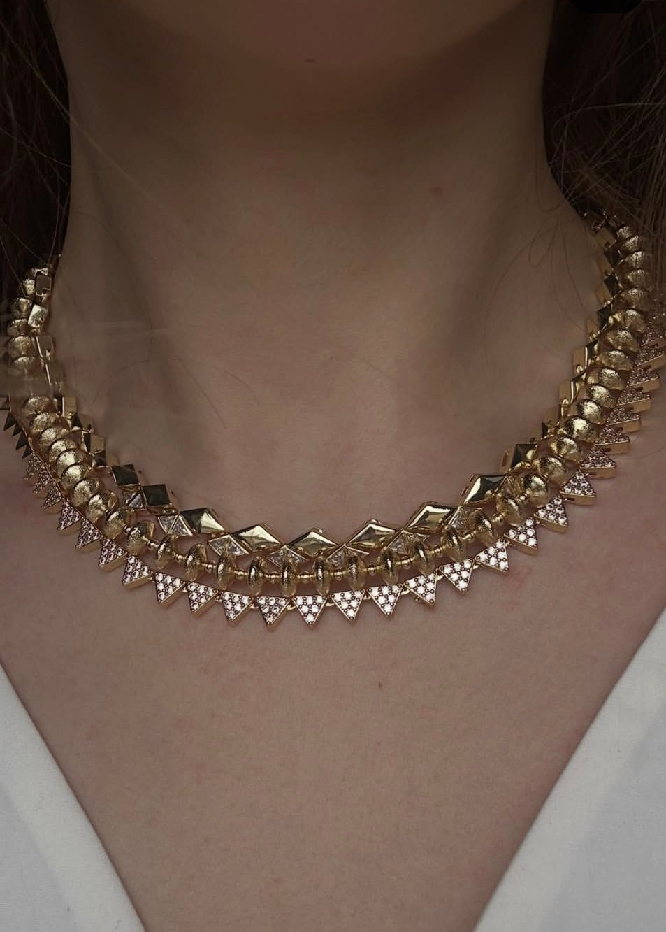 Gold necklace with diamond-like stones worn by a person