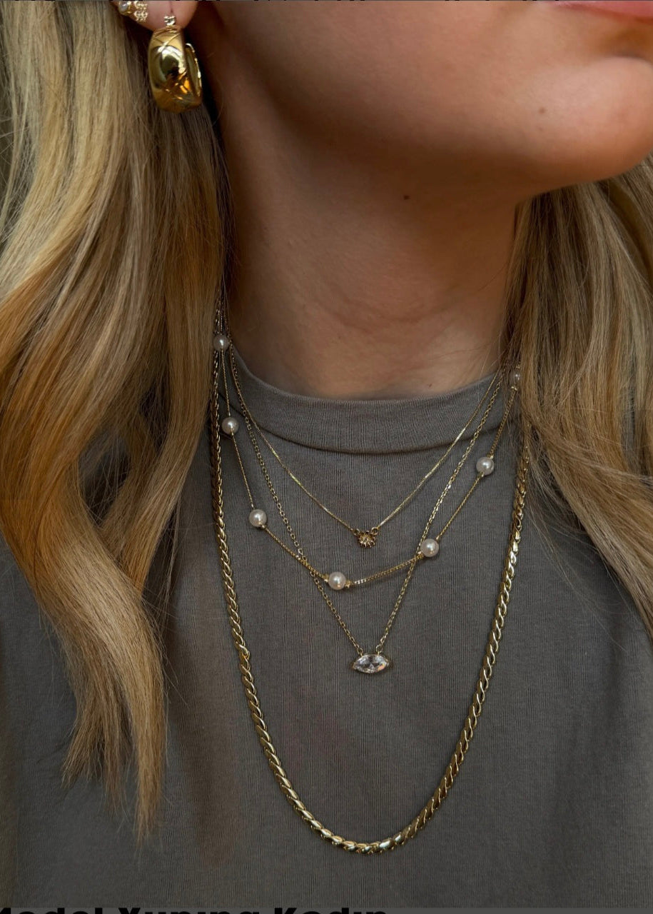 Gold pearl station necklace with spaced bead details on delicate chain displayed on neutral background