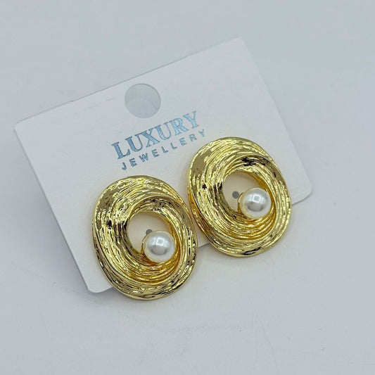 Gold swirl stud earrings with pearl center on white background
