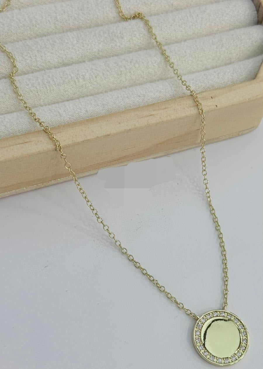 Gold round pendant necklace with zirconia halo circle charm on delicate chain displayed on neutral background