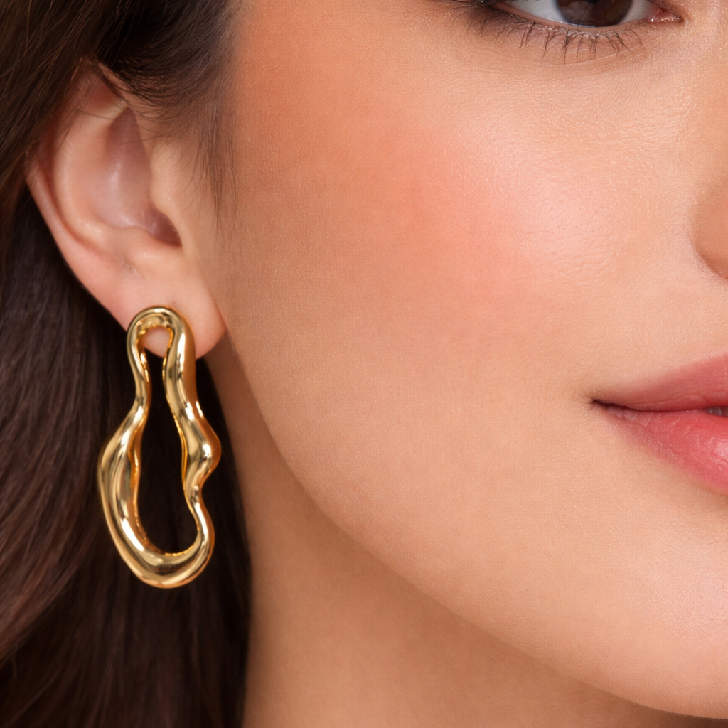 Gold abstract wave drop earrings worn on ear, sculptural non tarnish water resistant statement jewellery