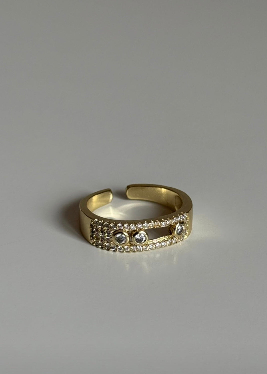 Gold ring with embedded stones on a gray background