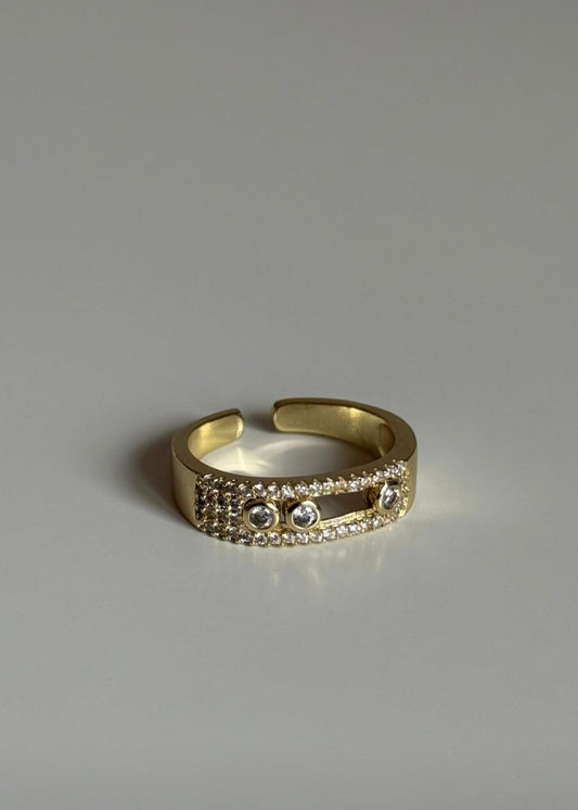 Gold ring with embedded stones on a gray background