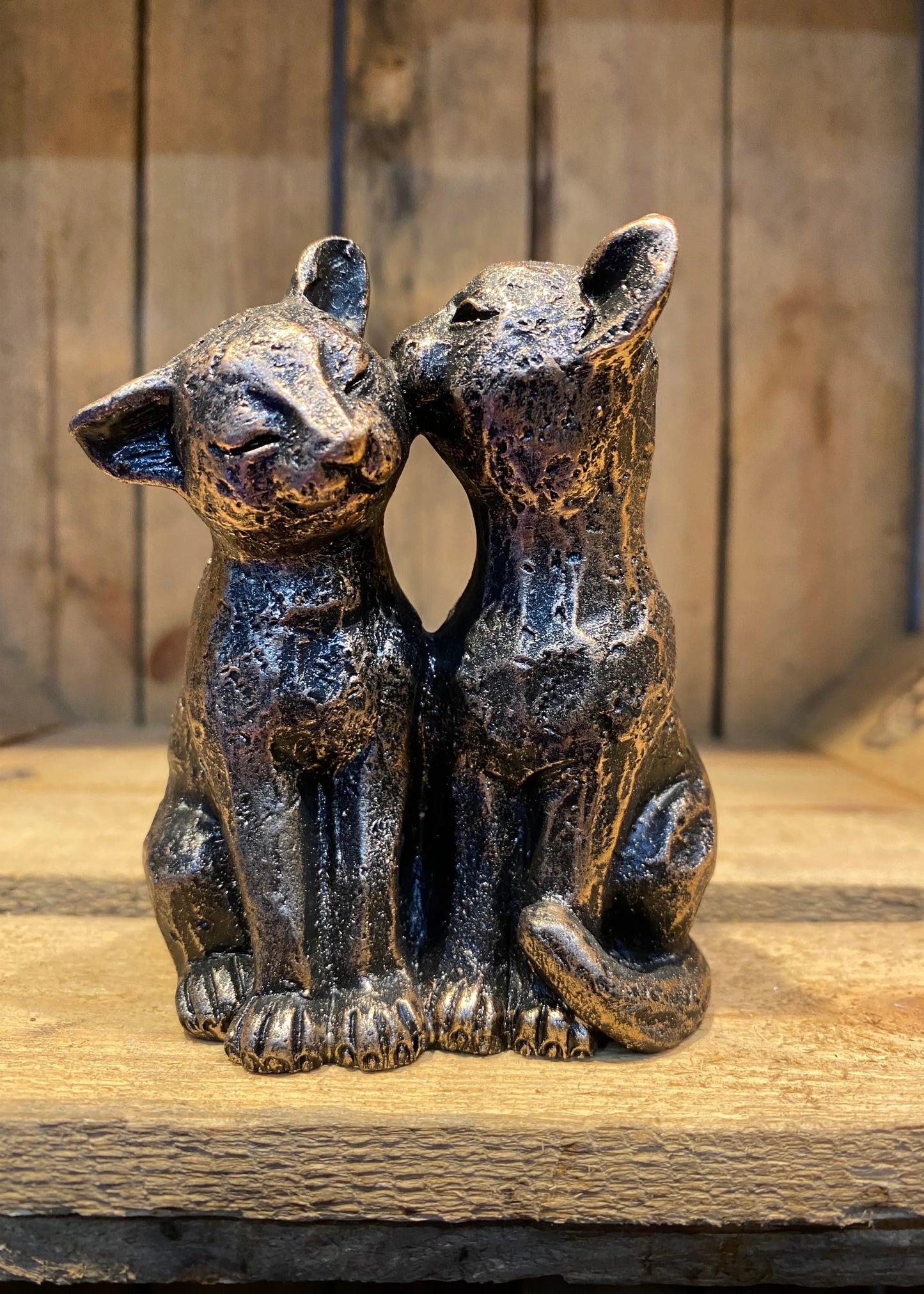 Miniature bronze effect cat pair resin figurine sitting together in affectionate pose on wooden surface