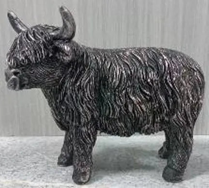 Miniature Highland cow bronze effect resin figurine with textured shaggy coat standing indoors