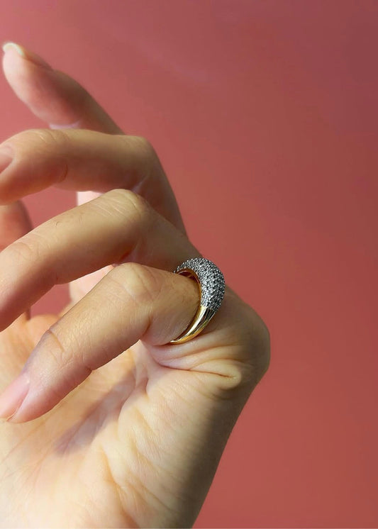 Hand wearing a ring with a pink background