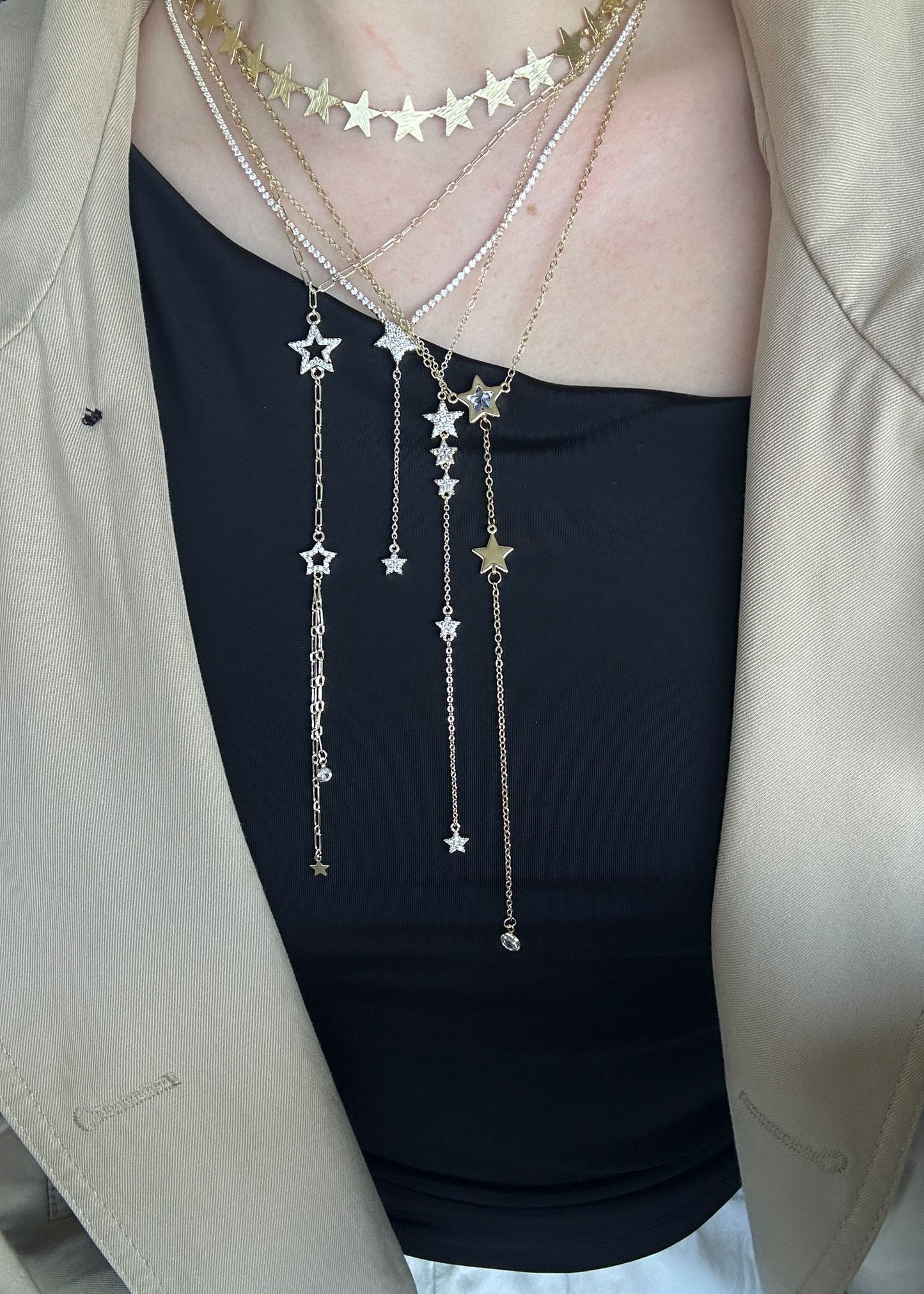 Star-shaped necklace worn by a person with a beige jacket and black top.