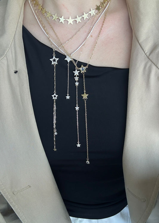 Star-shaped necklace worn by a person with a beige jacket and black top.