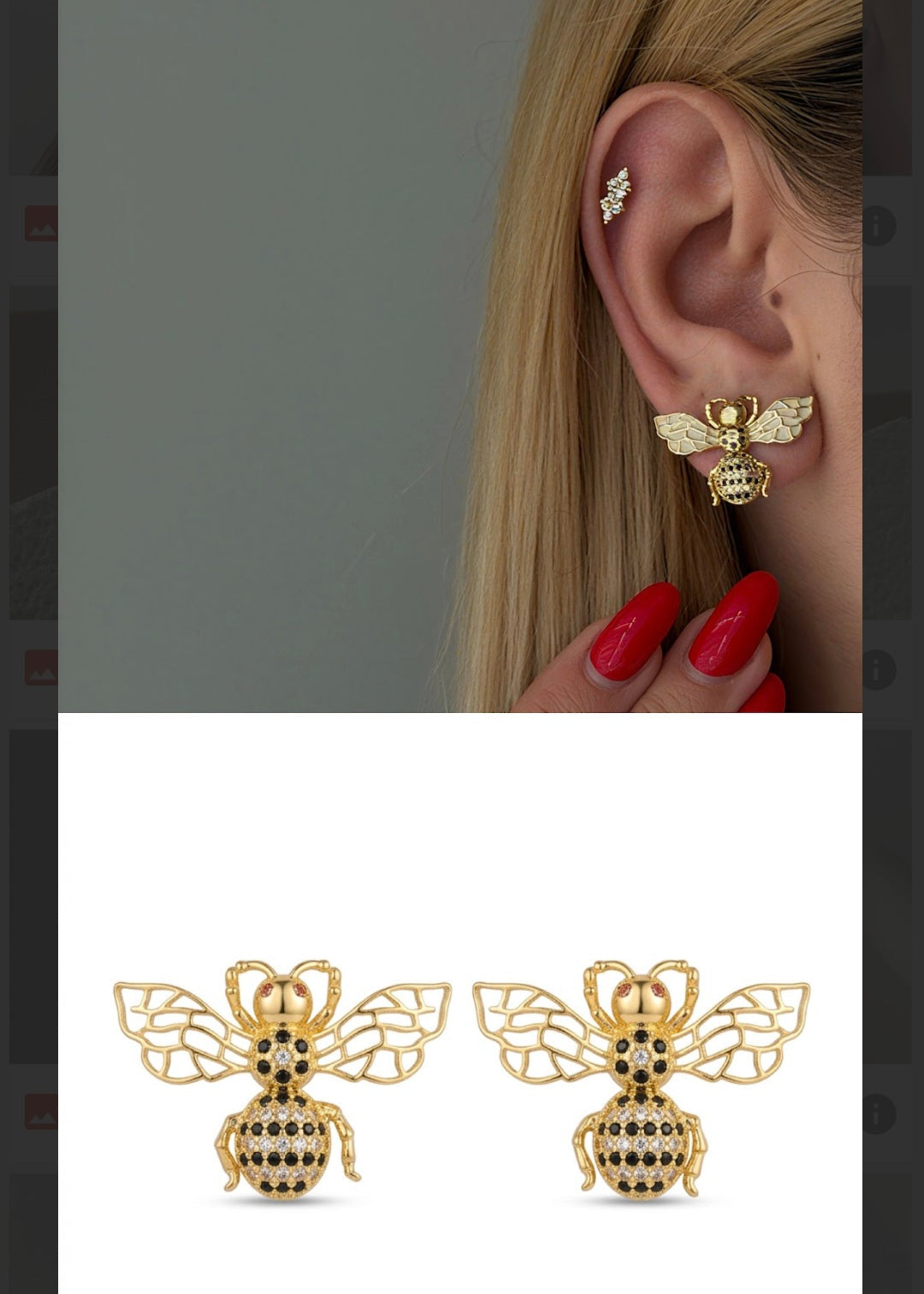 Gold bee-shaped earrings worn by a person with a plain background