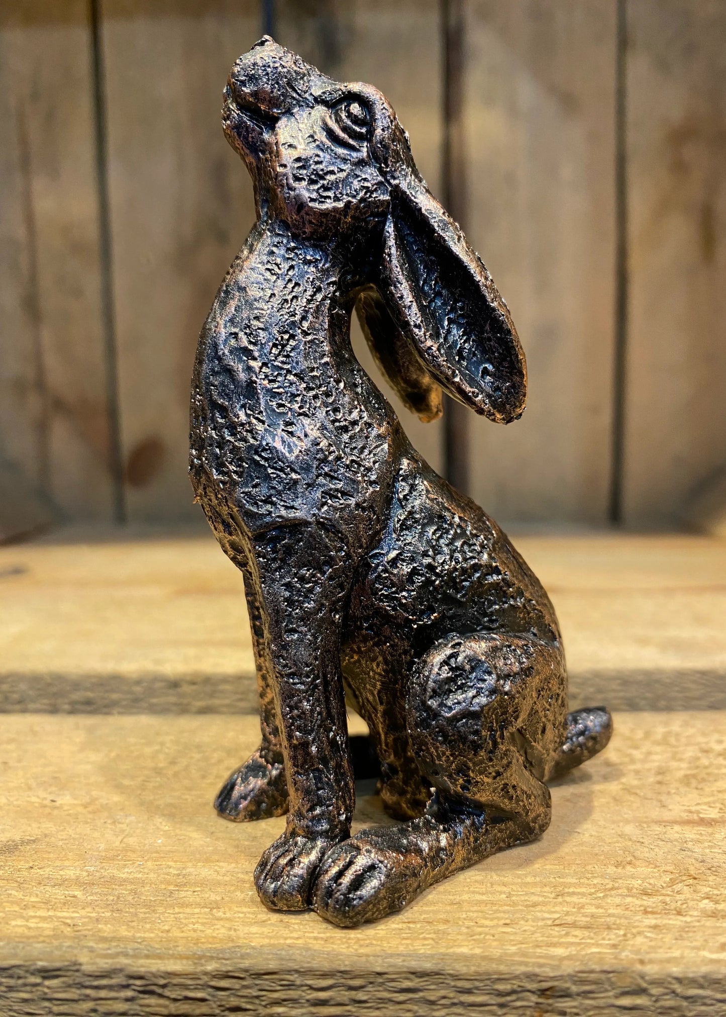 Bronze hare figurine on a wooden surface with a rustic background