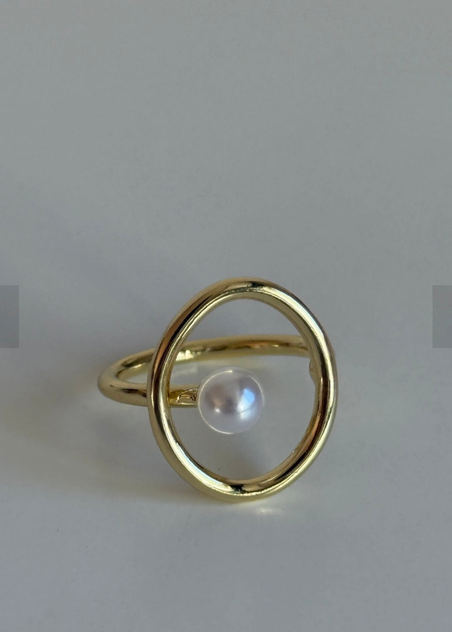 Gold ring with a pearl on a light gray background