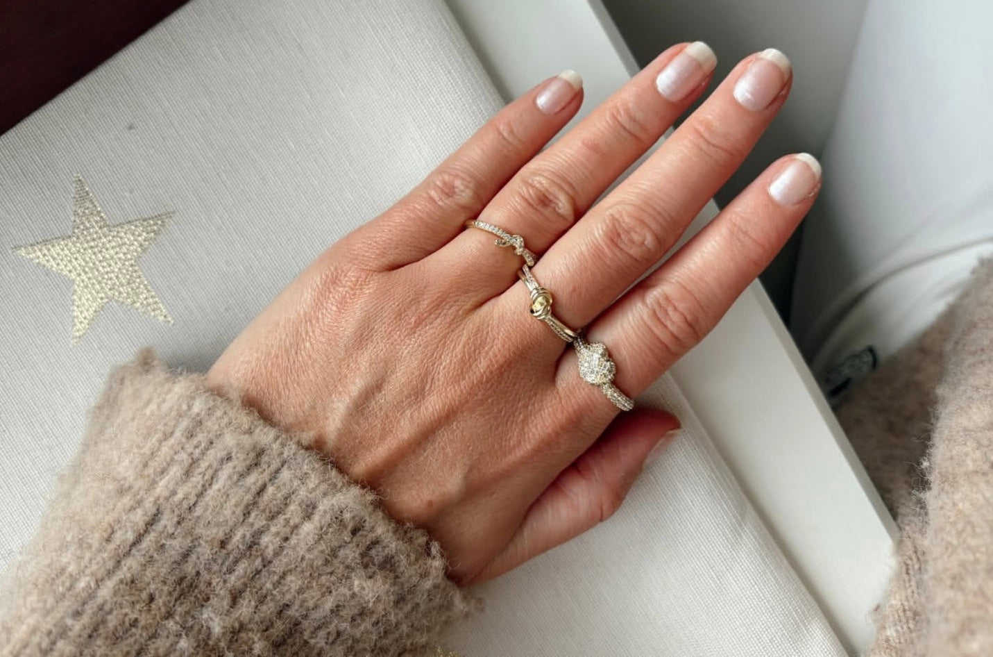 Hand wearing a ring with a star design in the background