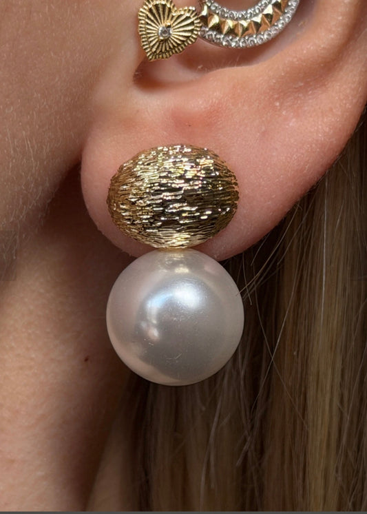 Gold and pearl earring worn by a person