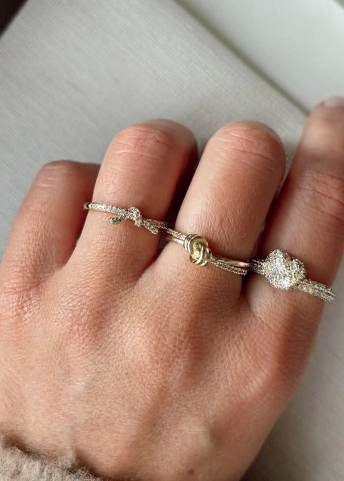 Hand wearing two silver rings on a light gray surface
