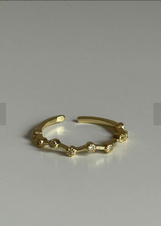 Gold ring with small diamonds on a grey background
