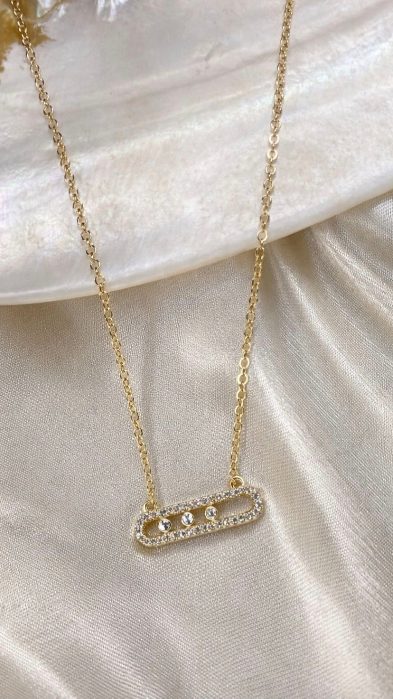 Gold necklace with a bar pendant on a marble surface