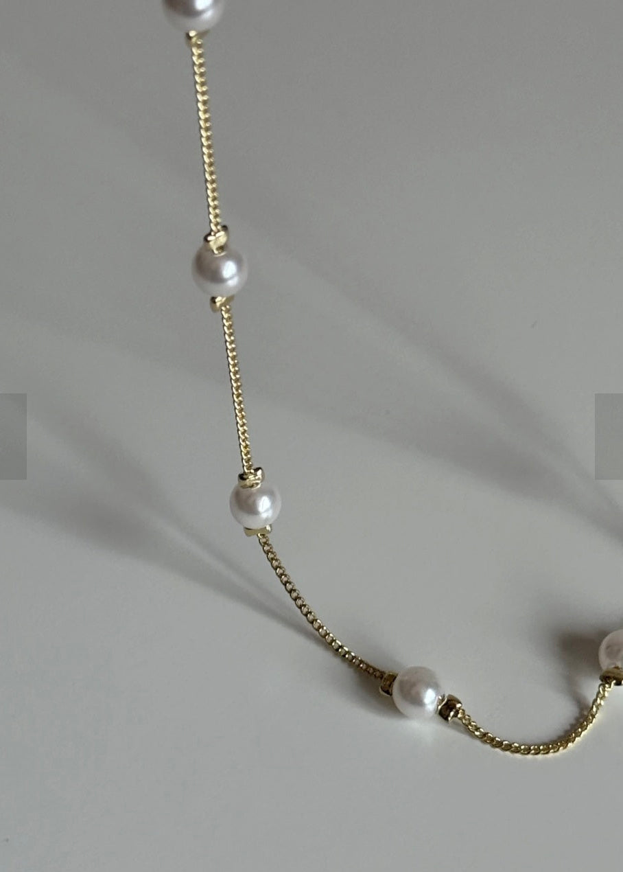 Necklace with pearls and gold chain on a gray background