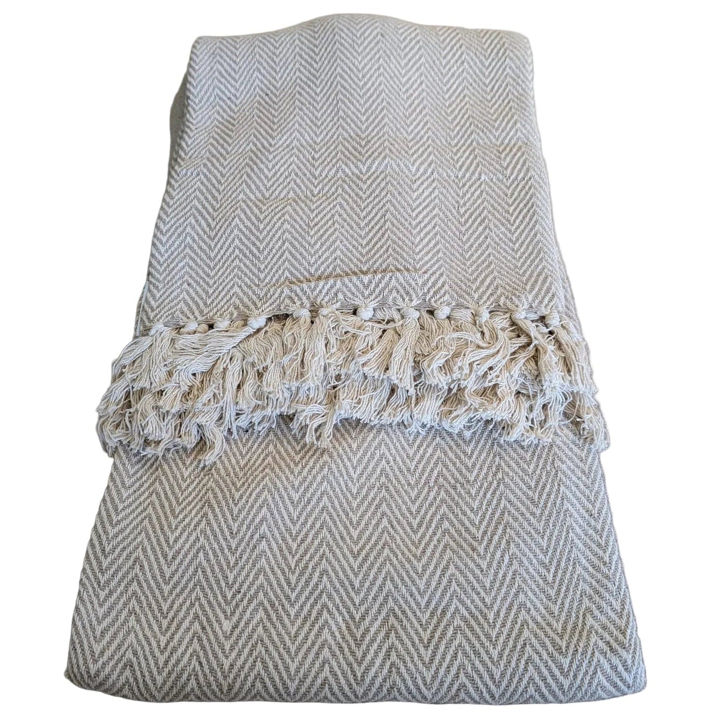 Folded beige and white textured blanket with lace trim on a beige surface