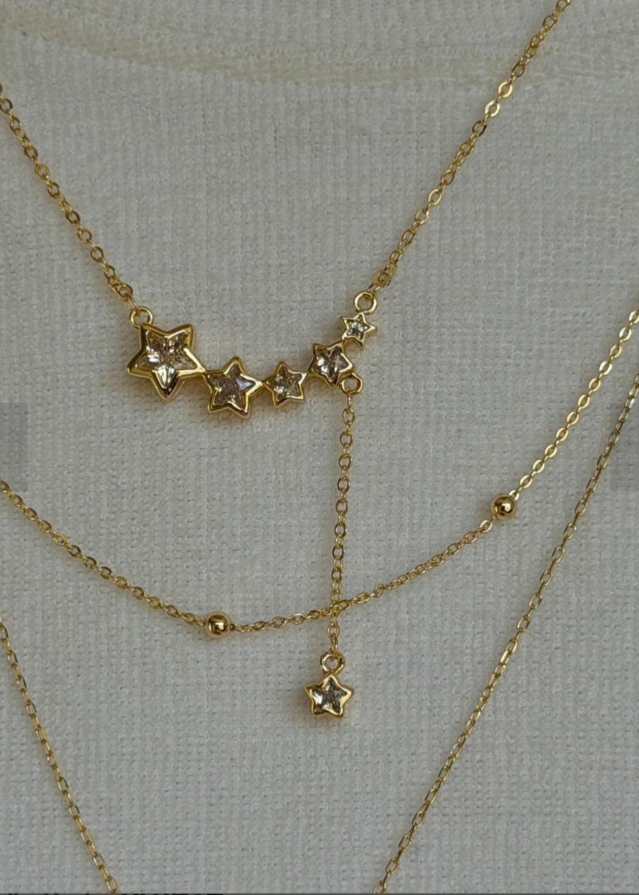 Gold necklaces with star pendants on a light gray background