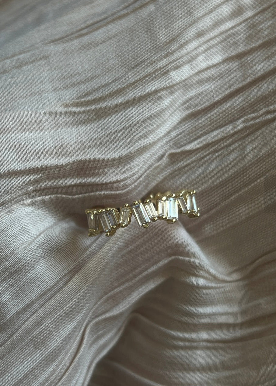 Gold earring on a textured beige fabric background