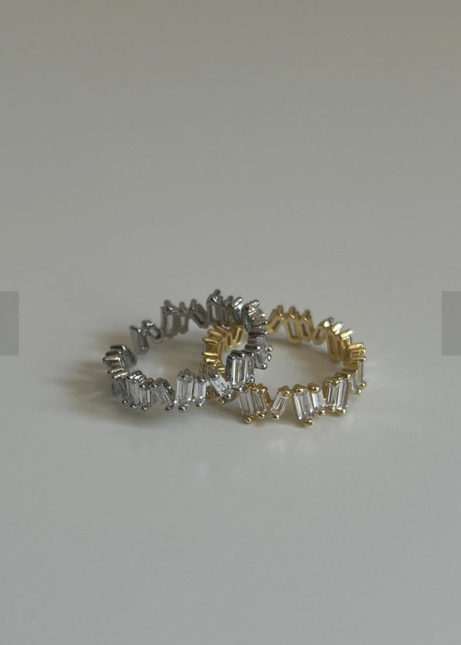 Two diamond rings, one gold and one silver, on a light gray background.