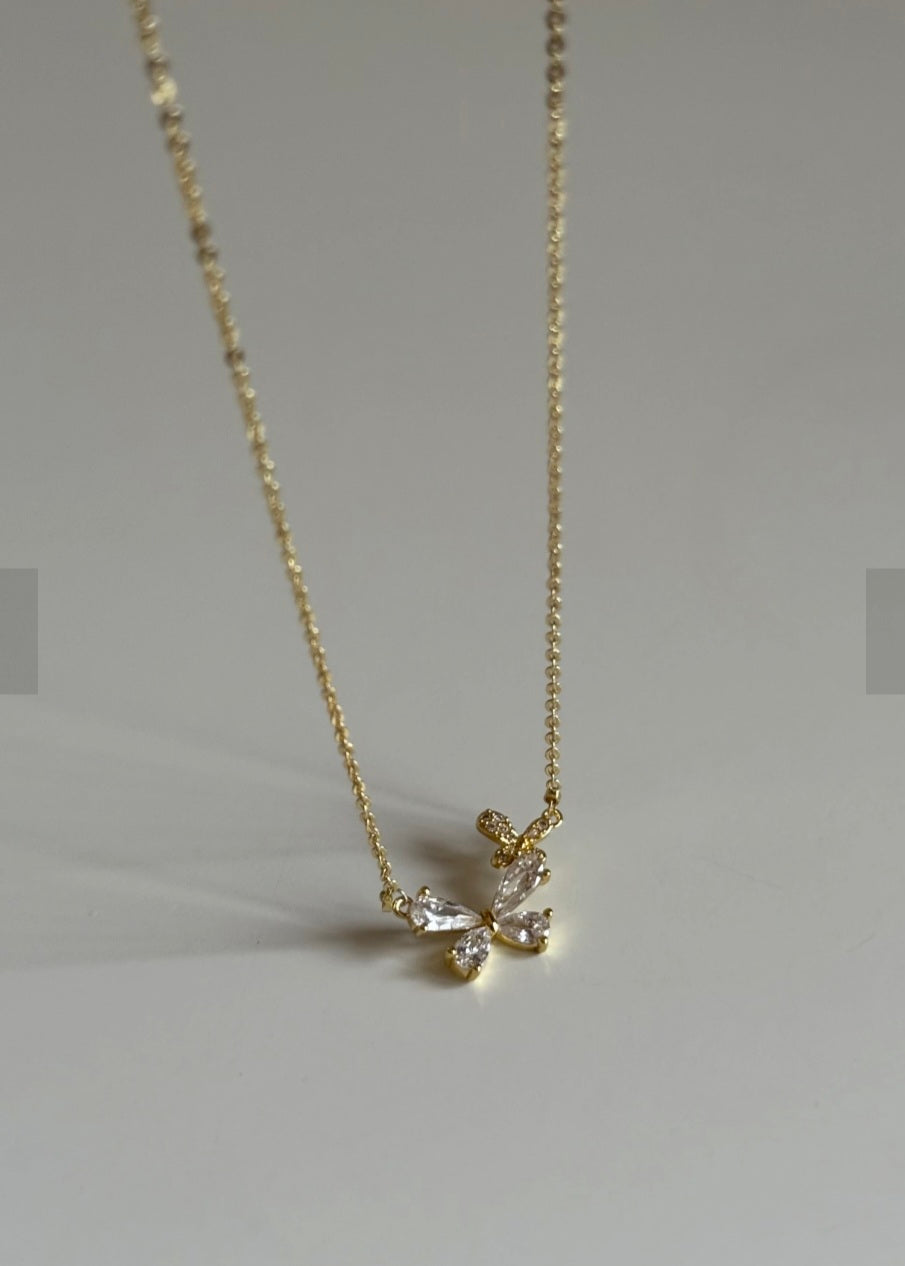 Gold necklace with a butterfly pendant on a gray background