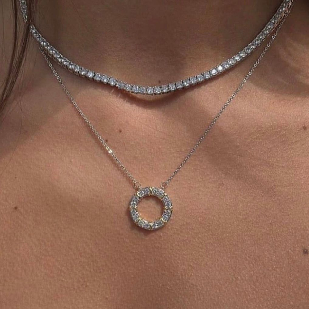 Close-up of a silver necklace with a circular pendant on a person's neck.
