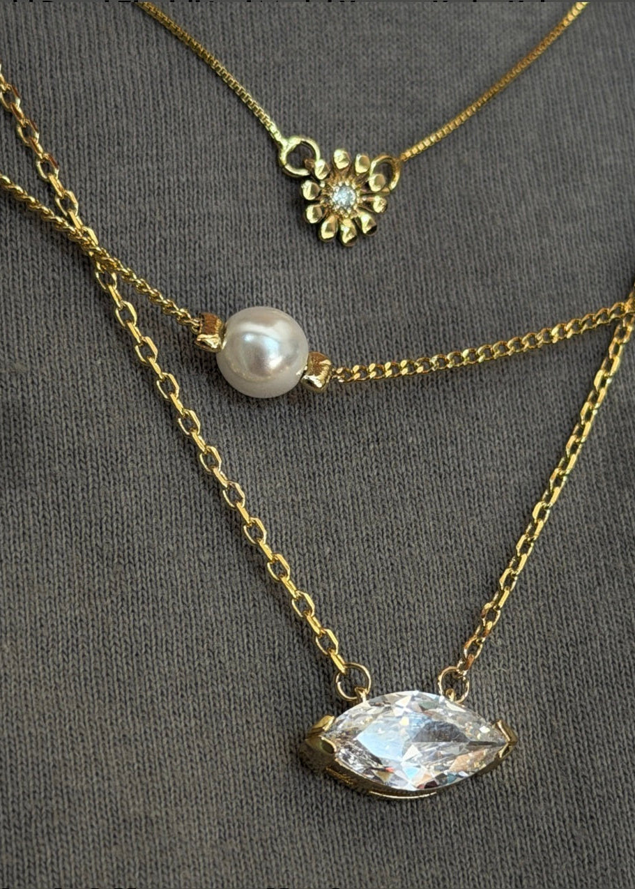 Gold necklaces with pearl and crystal pendants on a gray background