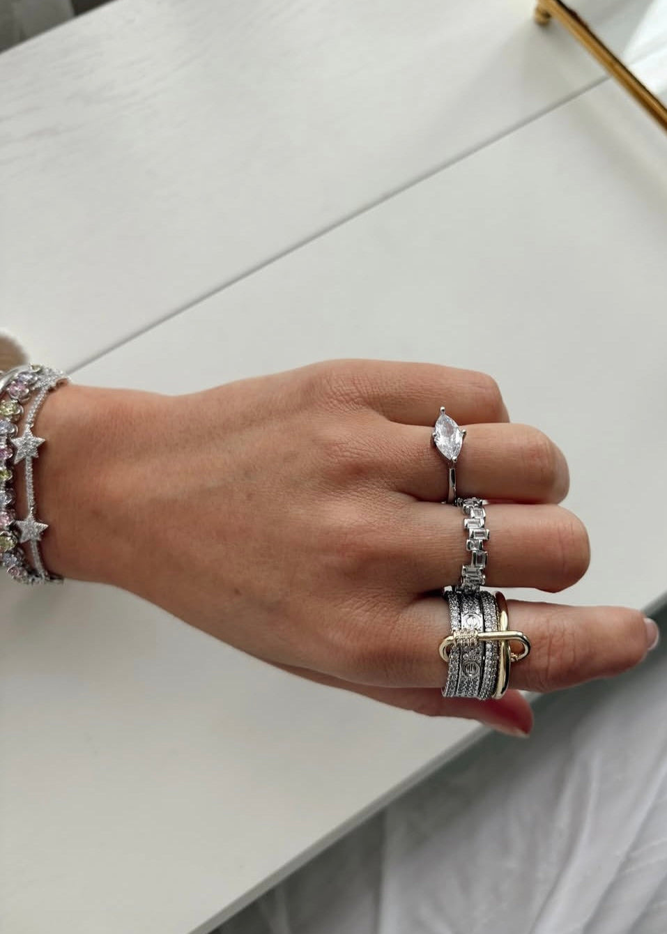 Hand wearing multiple rings on a light background