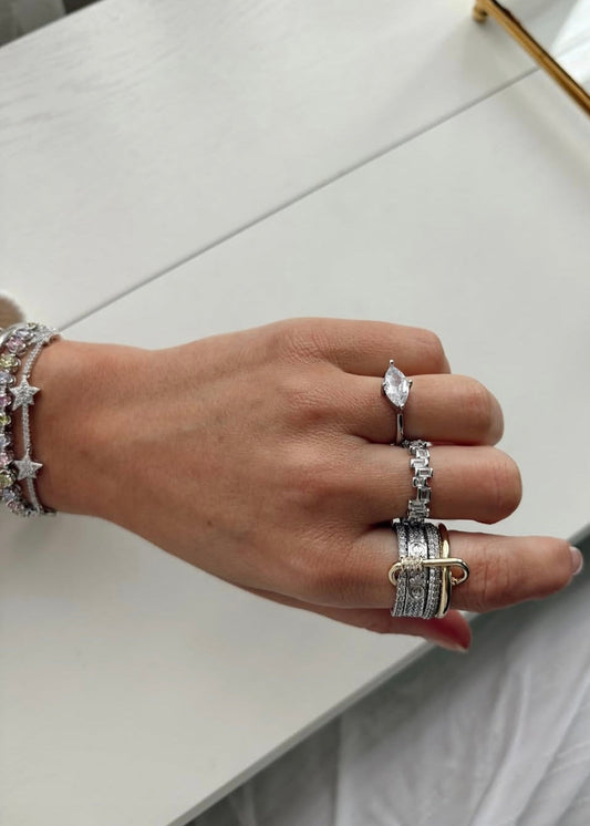 Hand wearing multiple rings on a light background
