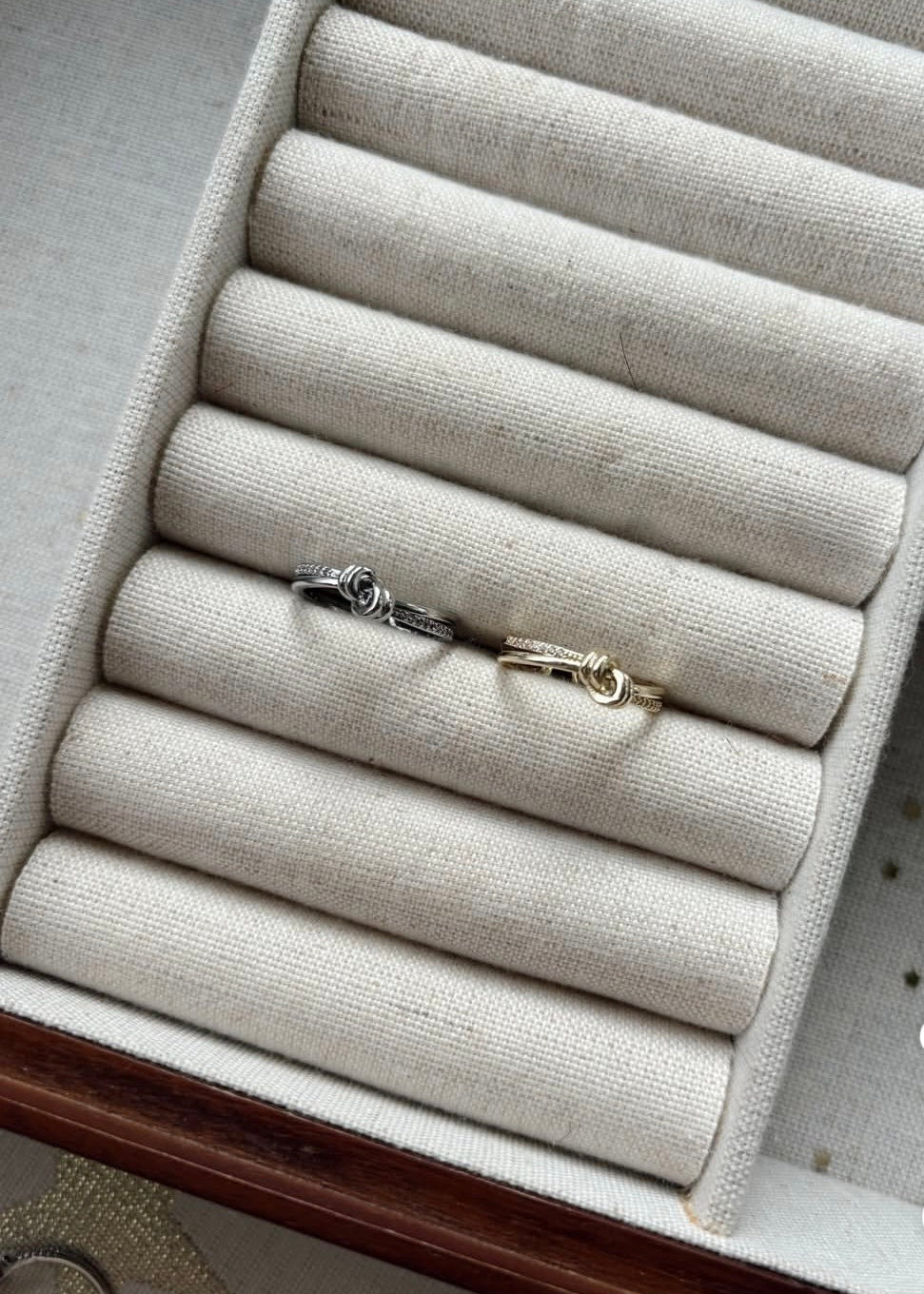 Jewelry box with rolled-up fabric compartments holding two bracelets.