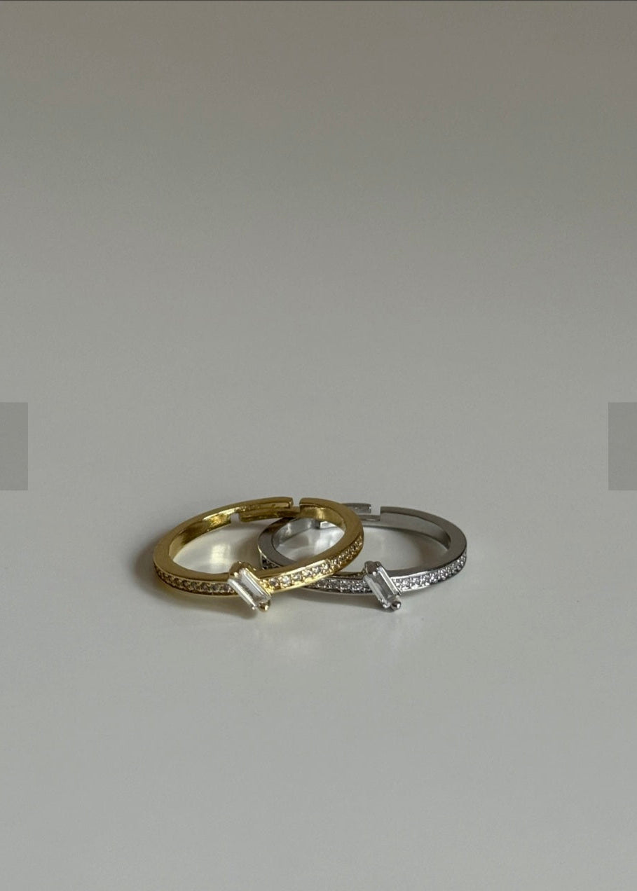 Two rings, one gold and one silver, on a light gray background