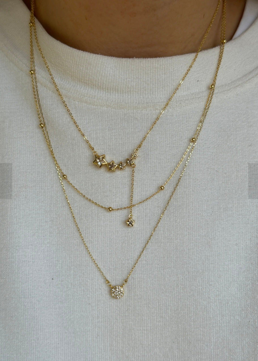 Two gold necklaces with small pendants on a white background