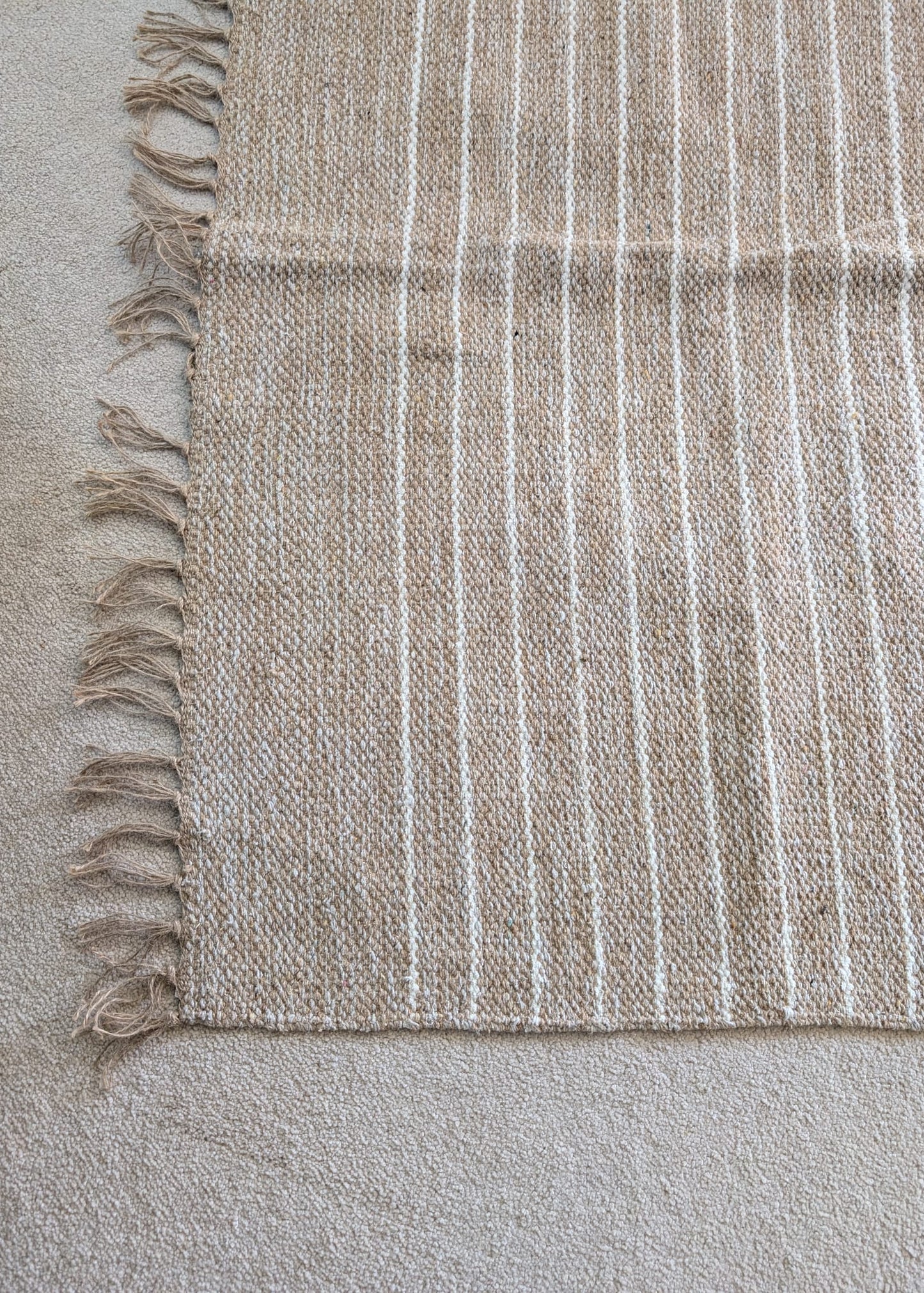 Textured fabric with white stripes and frayed edge on a neutral background