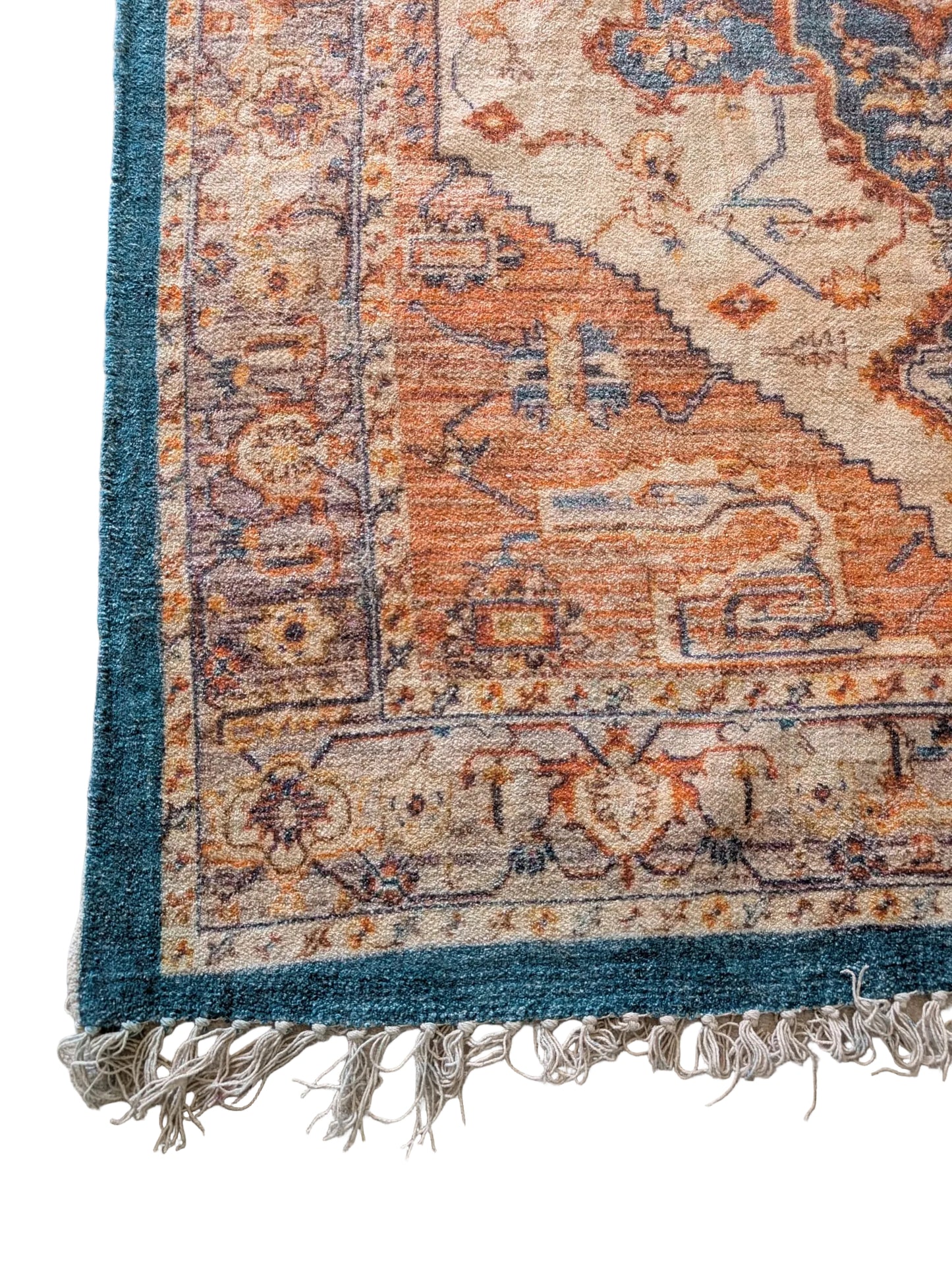 Close-up of a patterned rug with frayed edges on a light gray floor.
