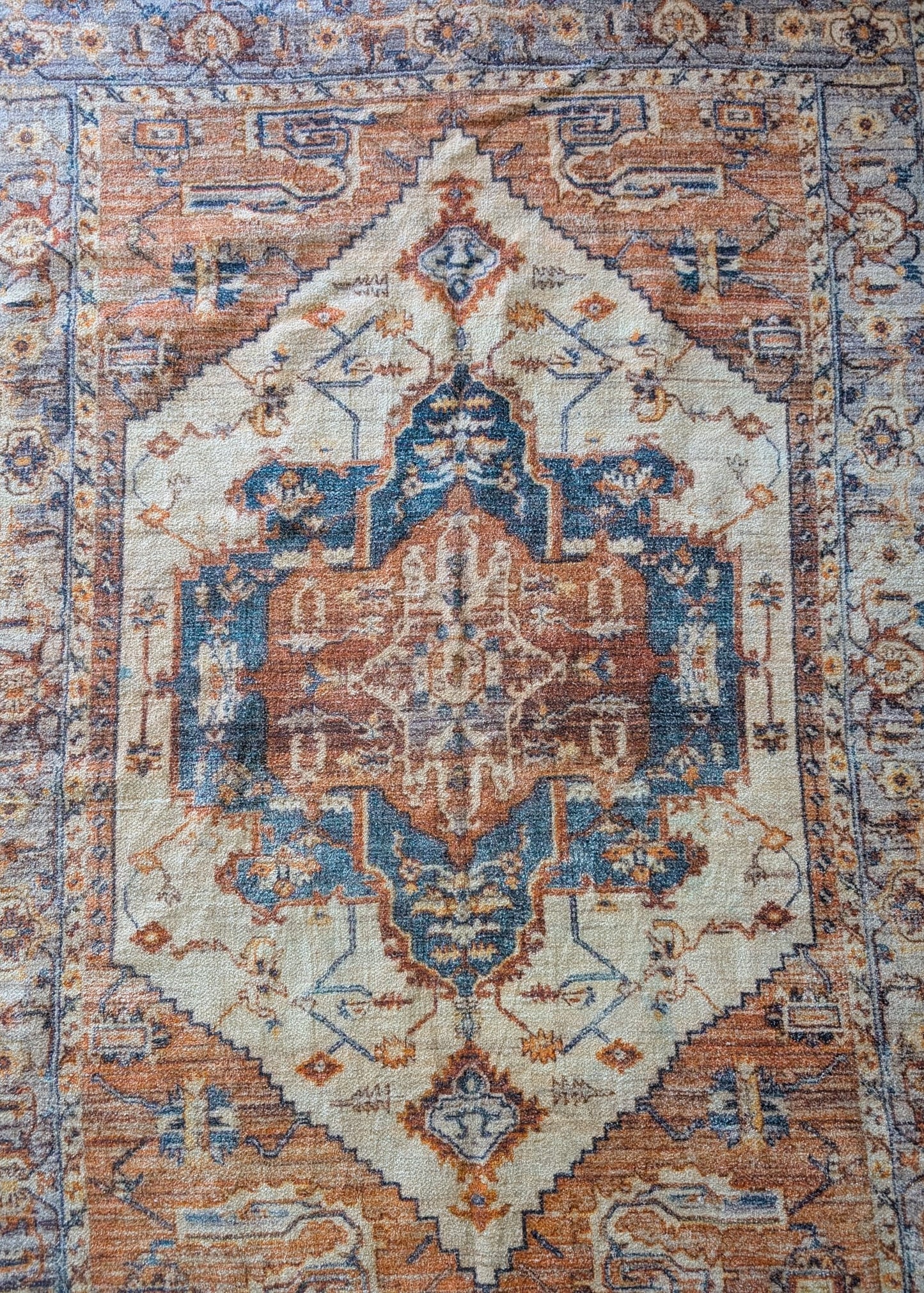 Decorative rug with intricate patterns in blue, brown, and beige.