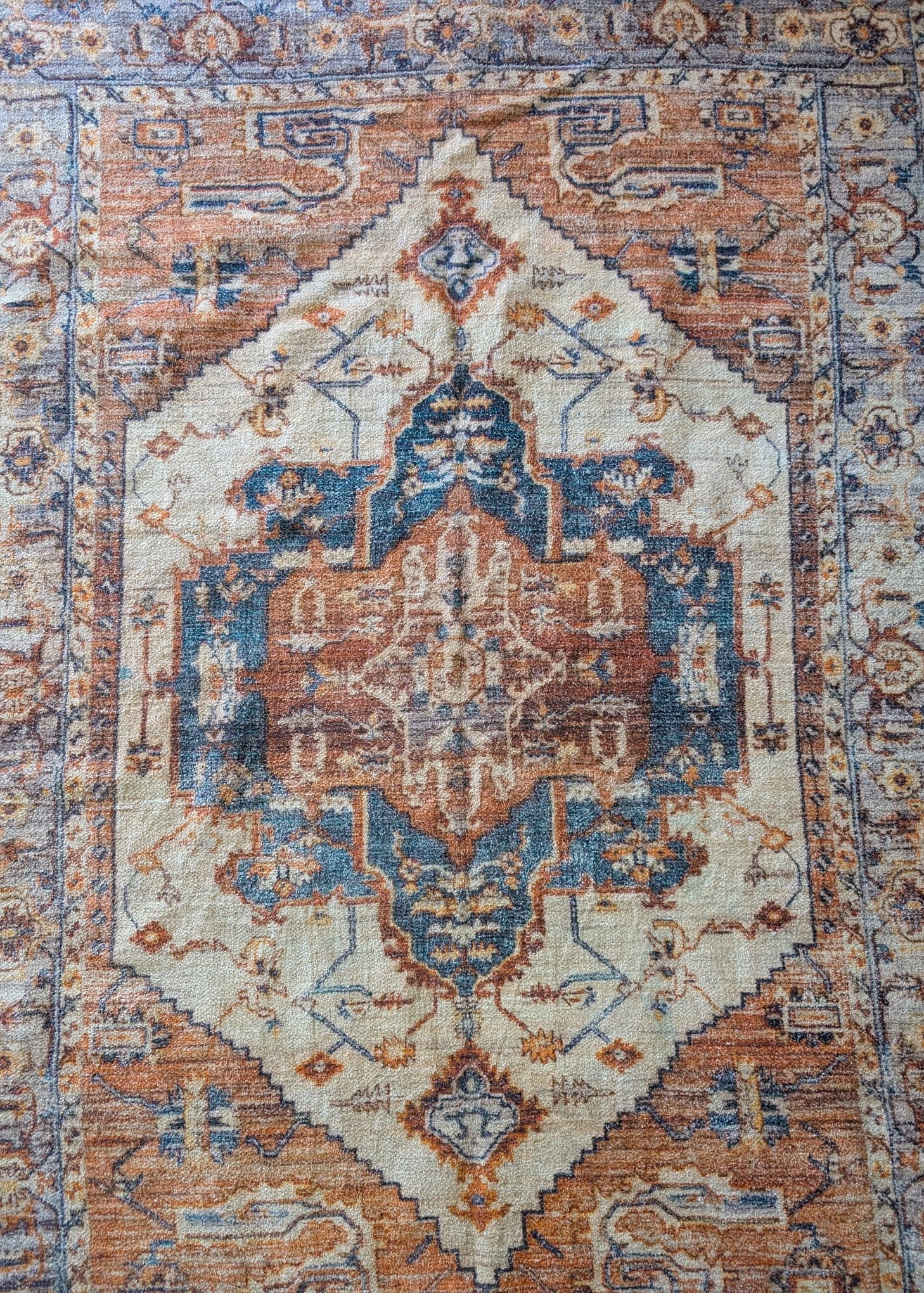 Decorative rug with intricate patterns in blue, brown, and beige.