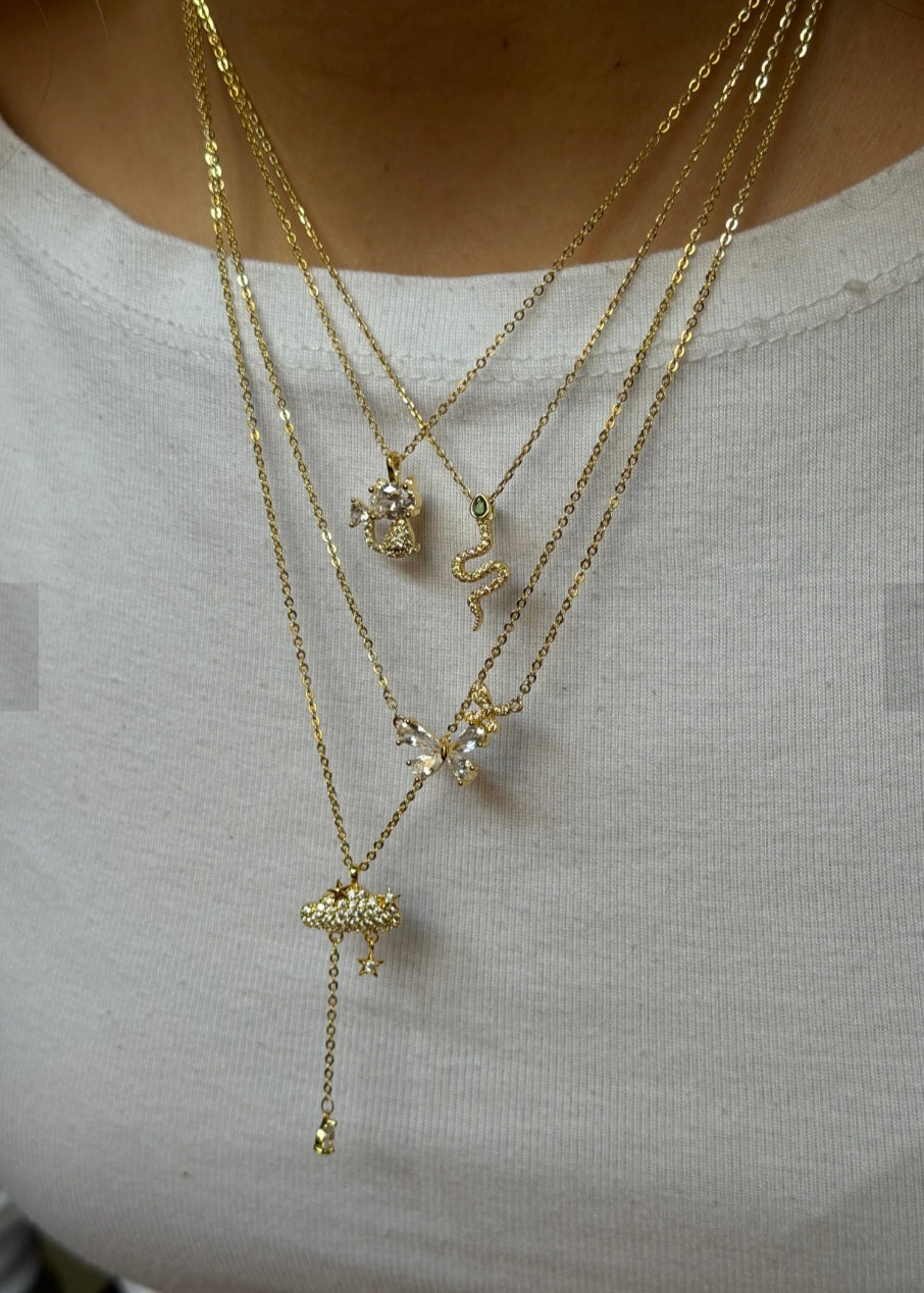 Layered gold necklaces with charms on a plain background