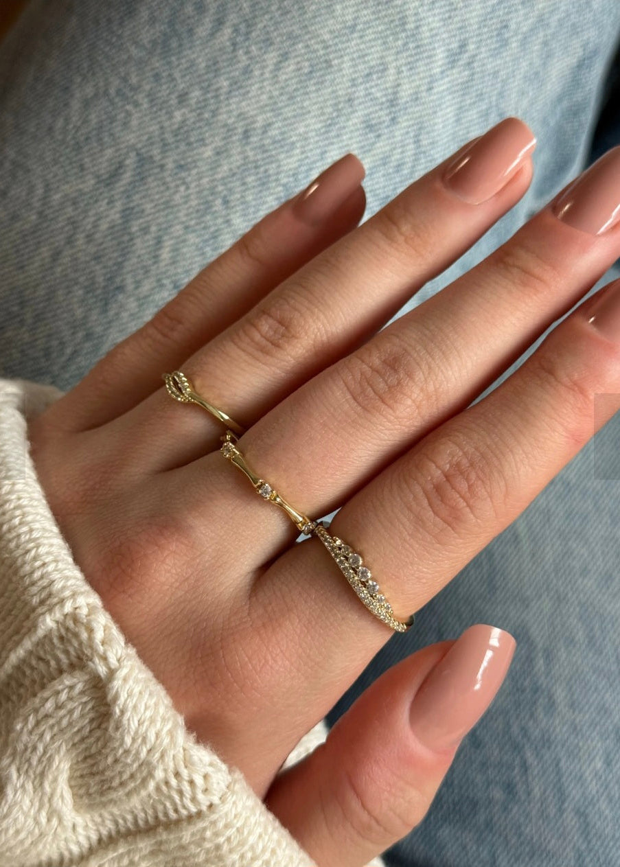 Hand wearing two gold rings with a blurred background